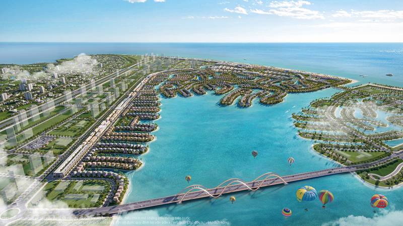 Phối cảnh tổng thể khu Vịnh Ngọc – The Green Bay nhìn từ trên cao: đại lộ và dãy phố thương mại, biển hồ xanh ngọc, các đảo biệt thự, cầu vòm và khinh khí cầu